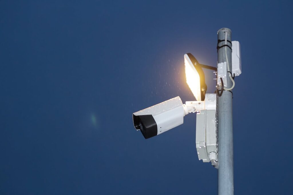 Low angle view of a security camera and light against a dark blue night sky.